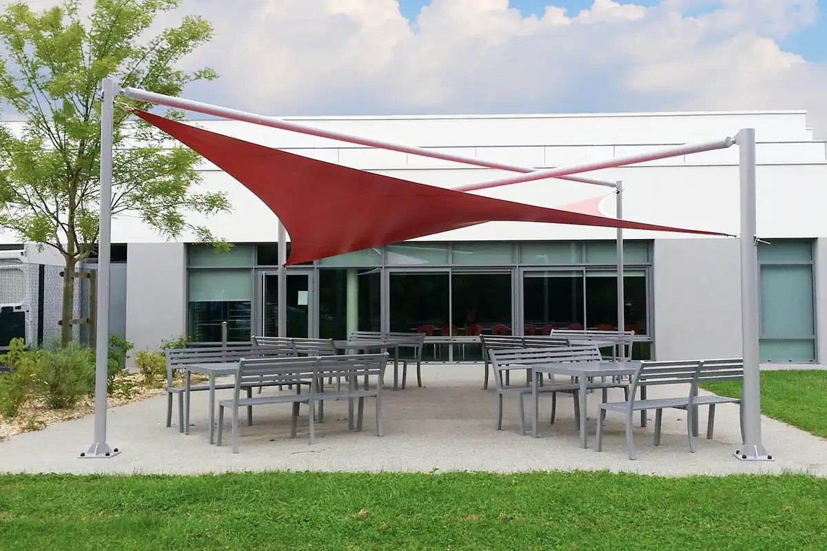 Grande voile d'ombrage rouge qui protège l'espace extérieur d'une entreprise