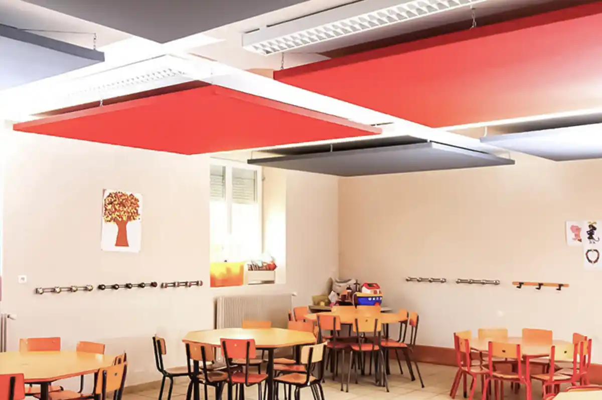 Panneaux acoustiques gris et rouge accrochés au plafond d'une cantine