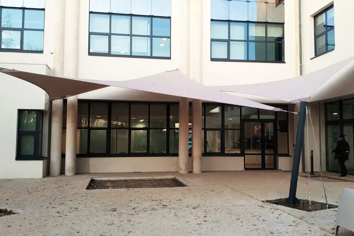 Voiles d'ombrage beige installées à l'entrée de la massif à Niort