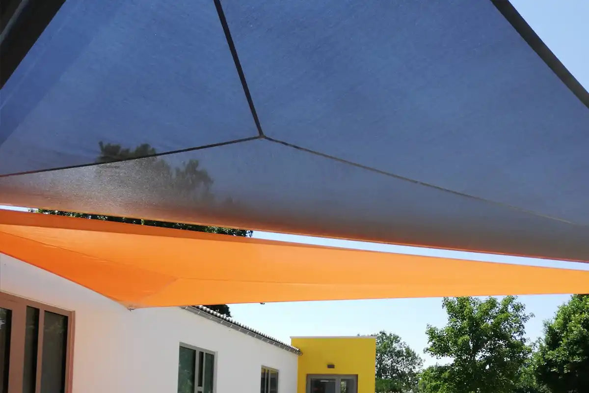Voiles d'ombrage orange et noir installées à l'entrée d'un bâtiment professionel