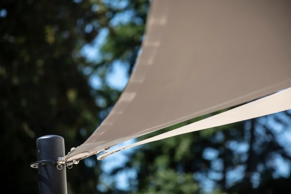 _Zoom sur deux voiles d'ombrage accrochés à un poteau en inox