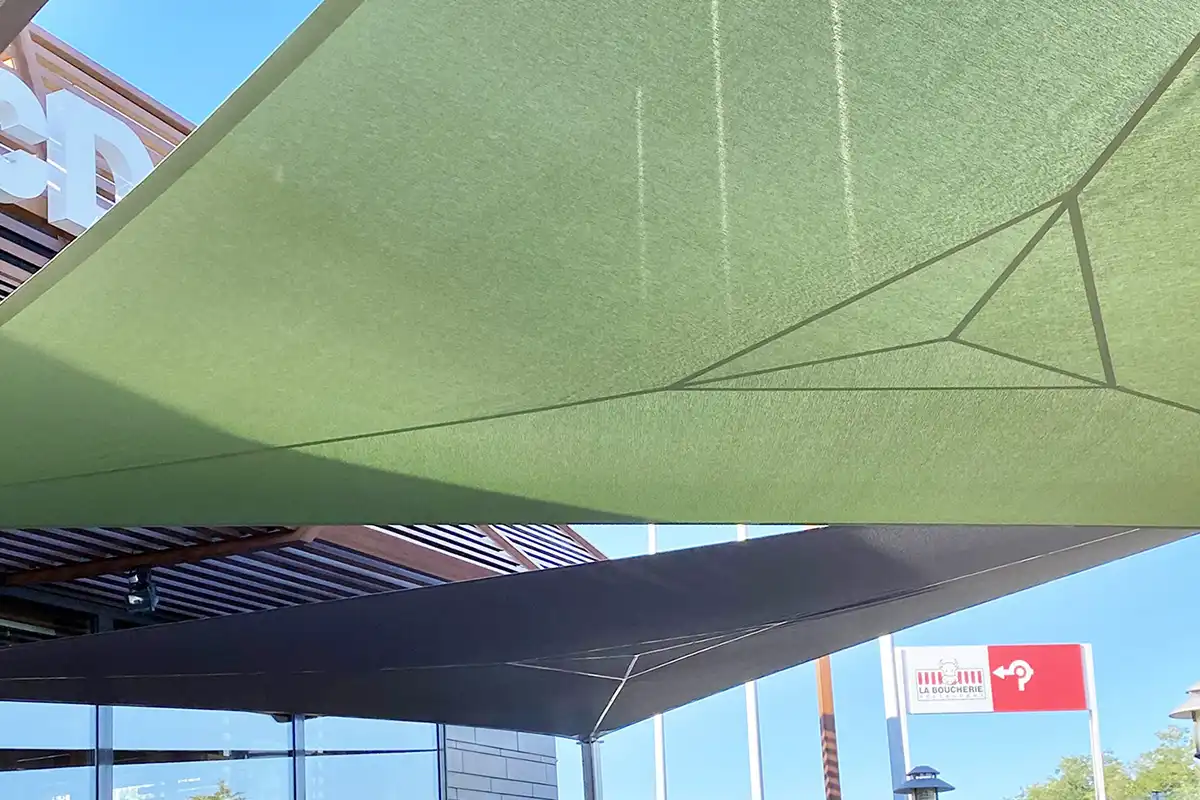 Zoom sur les voiles d'ombrage accrochés au-dessus de la terrasse d'un mac donald